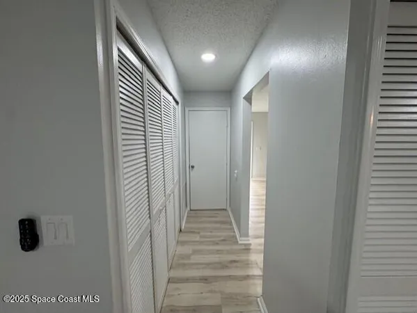 a view of a hallway with wooden floor and closet