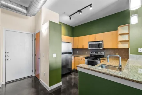 a kitchen with stainless steel appliances granite countertop a refrigerator a sink and a stove