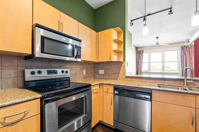 a kitchen with stainless steel appliances granite countertop a sink a stove a microwave and wooden cabinets