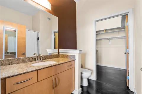 a bathroom with a granite countertop toilet a sink and a mirror