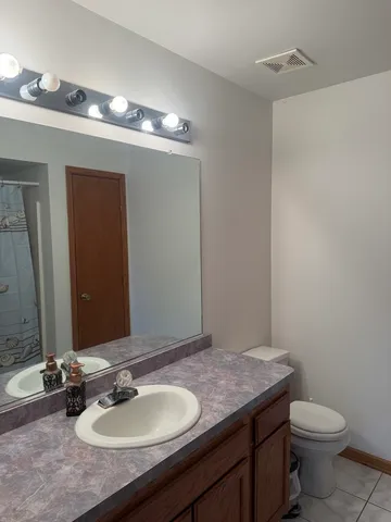 a bathroom with a granite countertop sink a toilet and a mirror