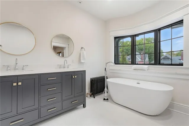 a spacious bathroom with a double vanity sink large mirror and bathtub