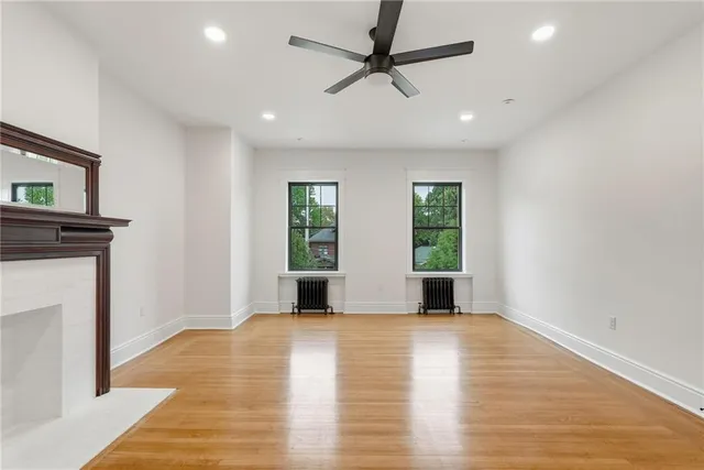 a view of empty room with wooden floor and fan