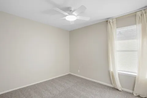 an empty room with a window and a ceiling fan
