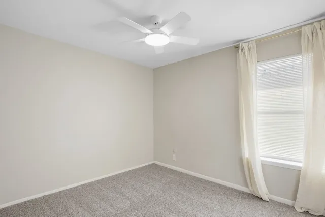 an empty room with a window and a ceiling fan