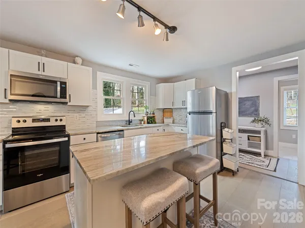 a kitchen with granite countertop white cabinets and stainless steel appliances