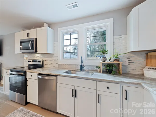 a kitchen with granite countertop a stove microwave and sink