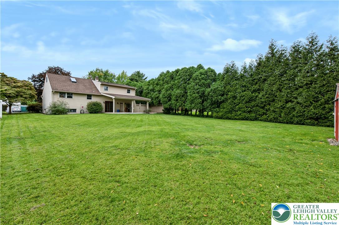 2750 Belaire Road Bethlehem, PA 18017 - Photo 4 of 56 A spacious green lawn stretches behind the home, bordered by mature privacy trees.