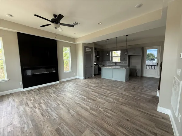 a view of a livingroom with a flat screen tv wooden floor and a kitchen