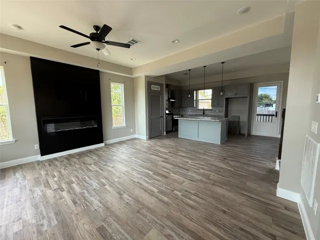 a view of a livingroom with a flat screen tv wooden floor and a kitchen