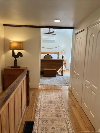 a hallway with a view of bedroom with wooden floor
