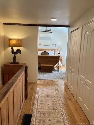 a hallway with a view of bedroom with wooden floor