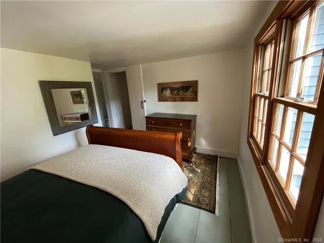 a bedroom with a bed and a large mirror on the dresser