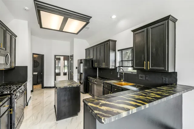 a kitchen with stainless steel appliances granite countertop a stove refrigerator and a sink