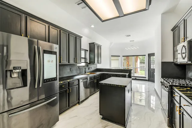 a kitchen with stainless steel appliances granite countertop a stove refrigerator and a sink