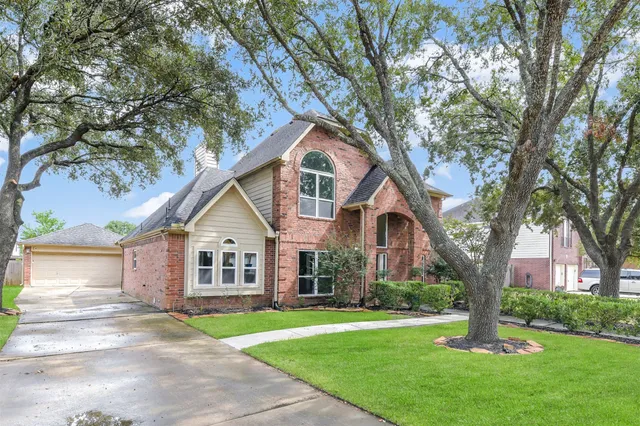 a front view of a house with a garden and trees