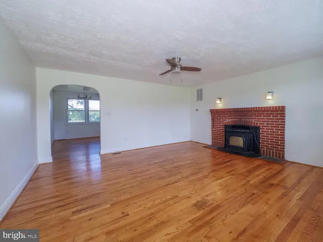 a view of empty room with wooden floor and fireplace