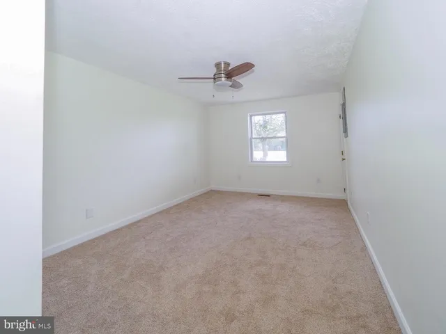 an empty room with a window and ceiling fan