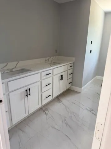a bathroom with a granite countertop sink and white cabinets