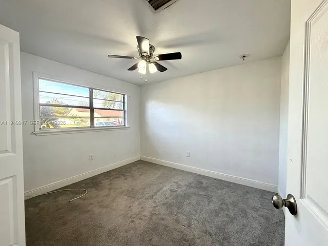 an empty room with windows and fan