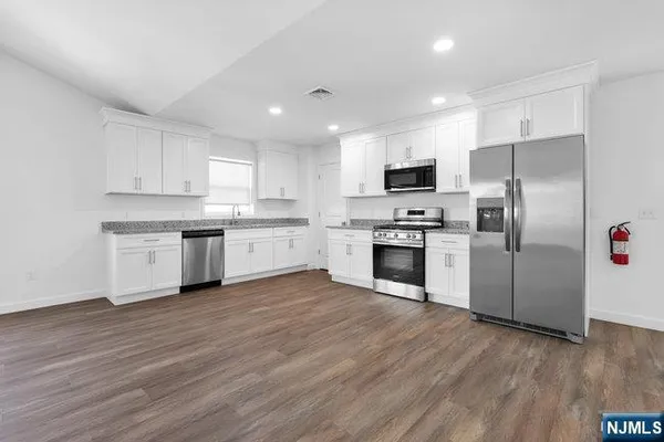 a kitchen with wooden floors stainless steel appliances and white cabinets