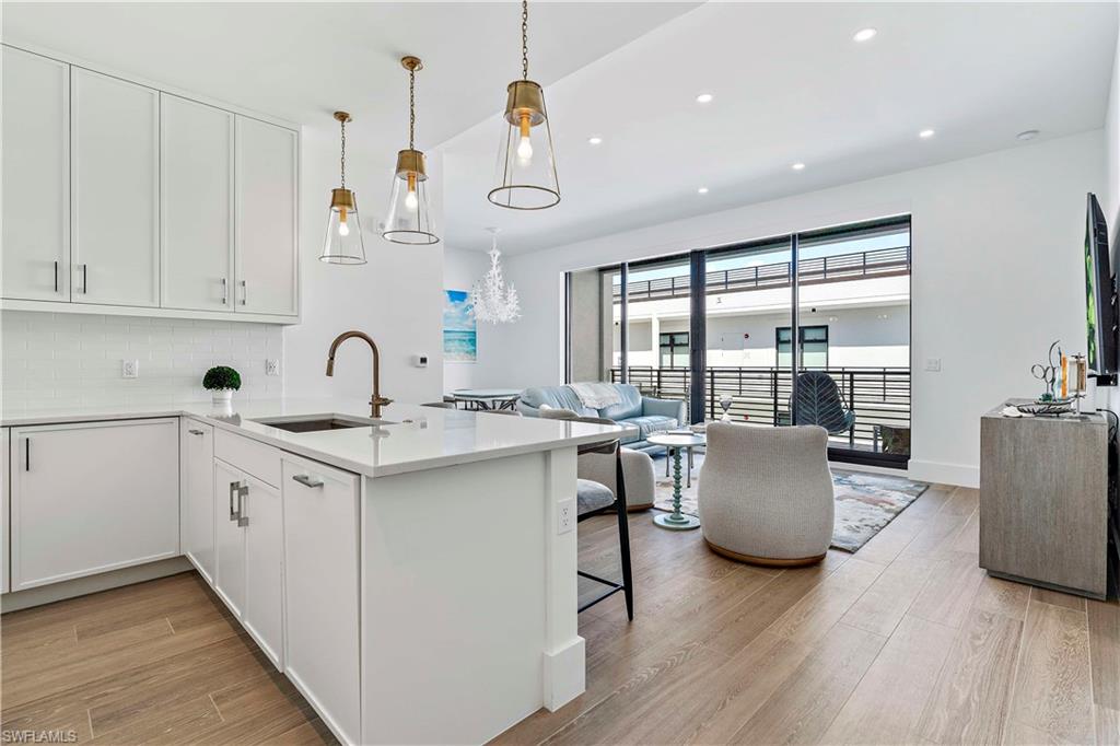 850 Central Avenue, Unit 310 Naples, FL 34102 - Photo 18 of 21 a kitchen with stainless steel appliances granite countertop a kitchen island a stove a sink a dining table and chairs