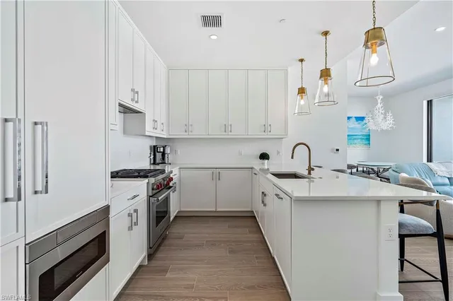 a kitchen with white cabinets sink and white stainless steel appliances
