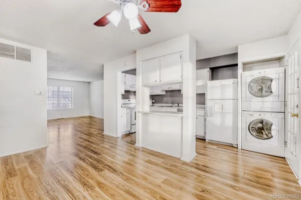 a view of kitchen and empty room with wooden floor