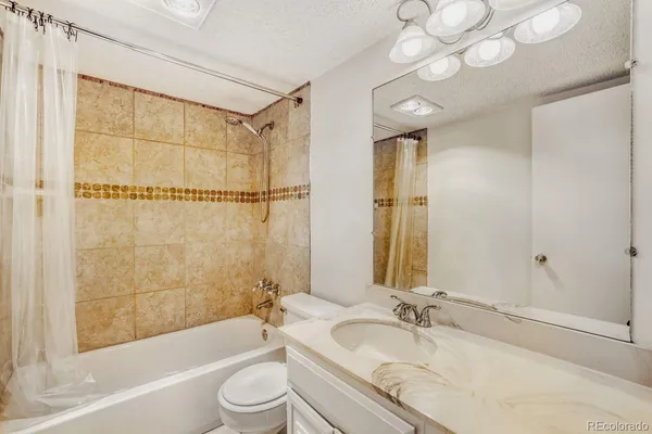 a bathroom with a granite countertop sink a toilet and shower