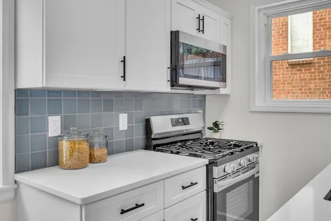 a kitchen with stainless steel appliances granite countertop a sink a stove and a white cabinets