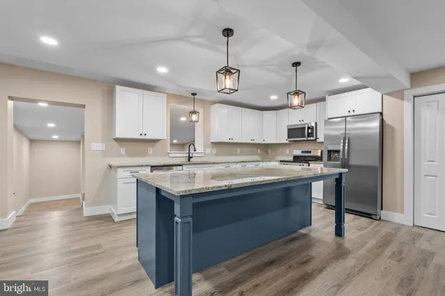 a kitchen with stainless steel appliances granite countertop a sink a stove a refrigerator and island with wooden floor