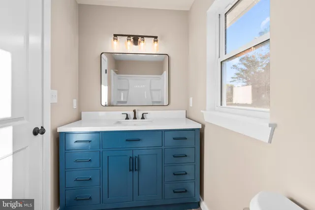 a bathroom with a toilet a sink a vanity and mirror