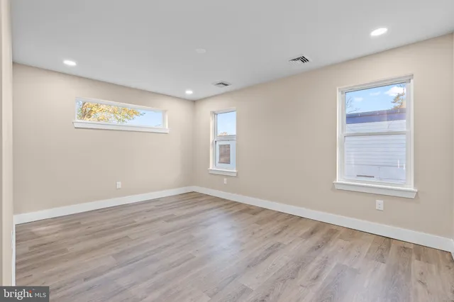 an empty room with wooden floor and windows