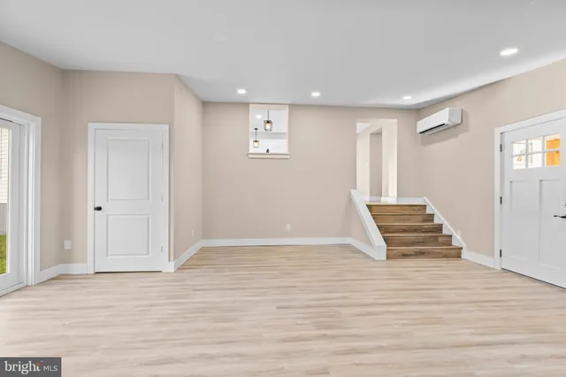a view of an empty room with wooden floor and window