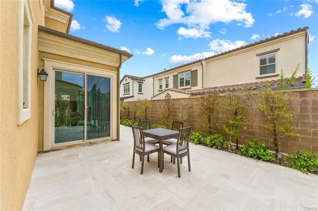 a patio with table and chairs and potted plants