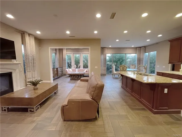 a living room with couches kitchen view and a wooden floor