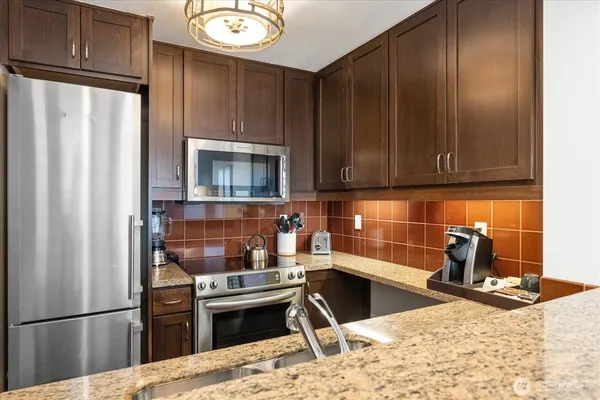 a kitchen with stainless steel appliances granite countertop a refrigerator stove and sink