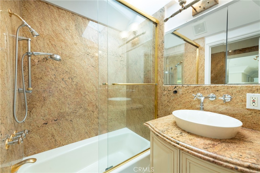 16379 Meadow Ridge Road West Encino, CA 91436 - Photo 27 of 40 a bathroom with a granite countertop sink a mirror and a bathtub