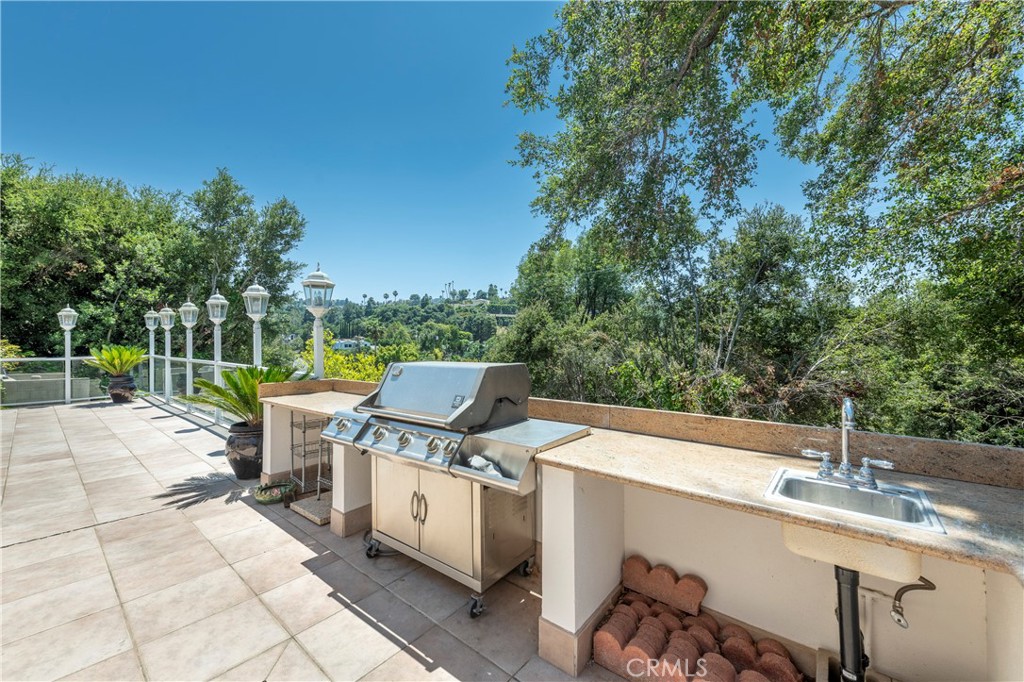 16379 Meadow Ridge Road West Encino, CA 91436 - Photo 36 of 40 a view of a patio with a table and chairs under an umbrella with large trees