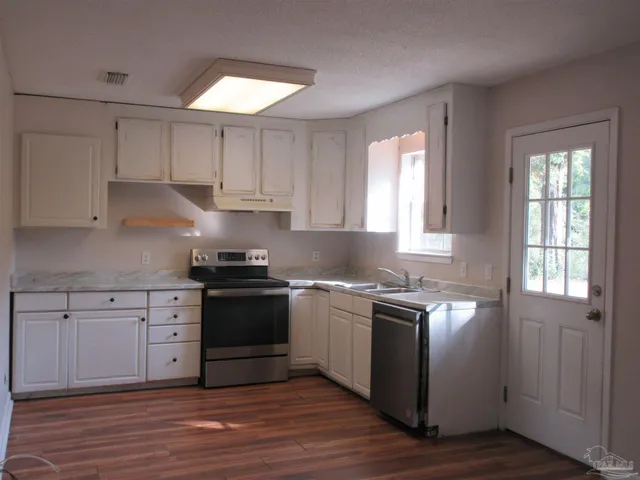 a kitchen with white cabinets and appliances