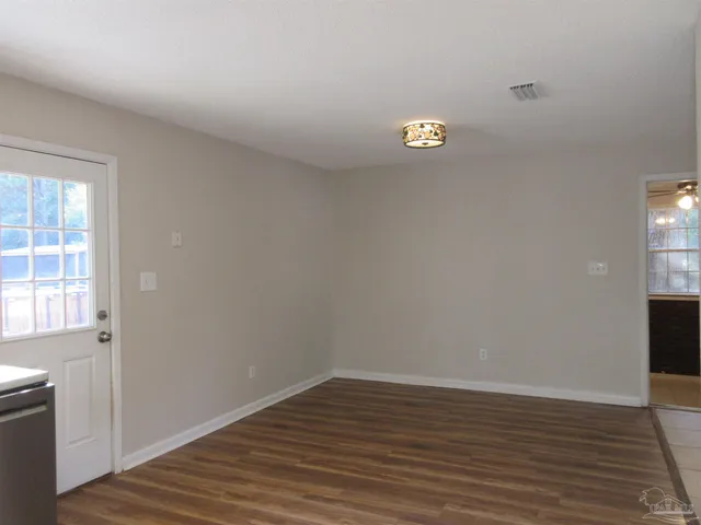 a view of an empty room with wooden floor and a ceiling fan