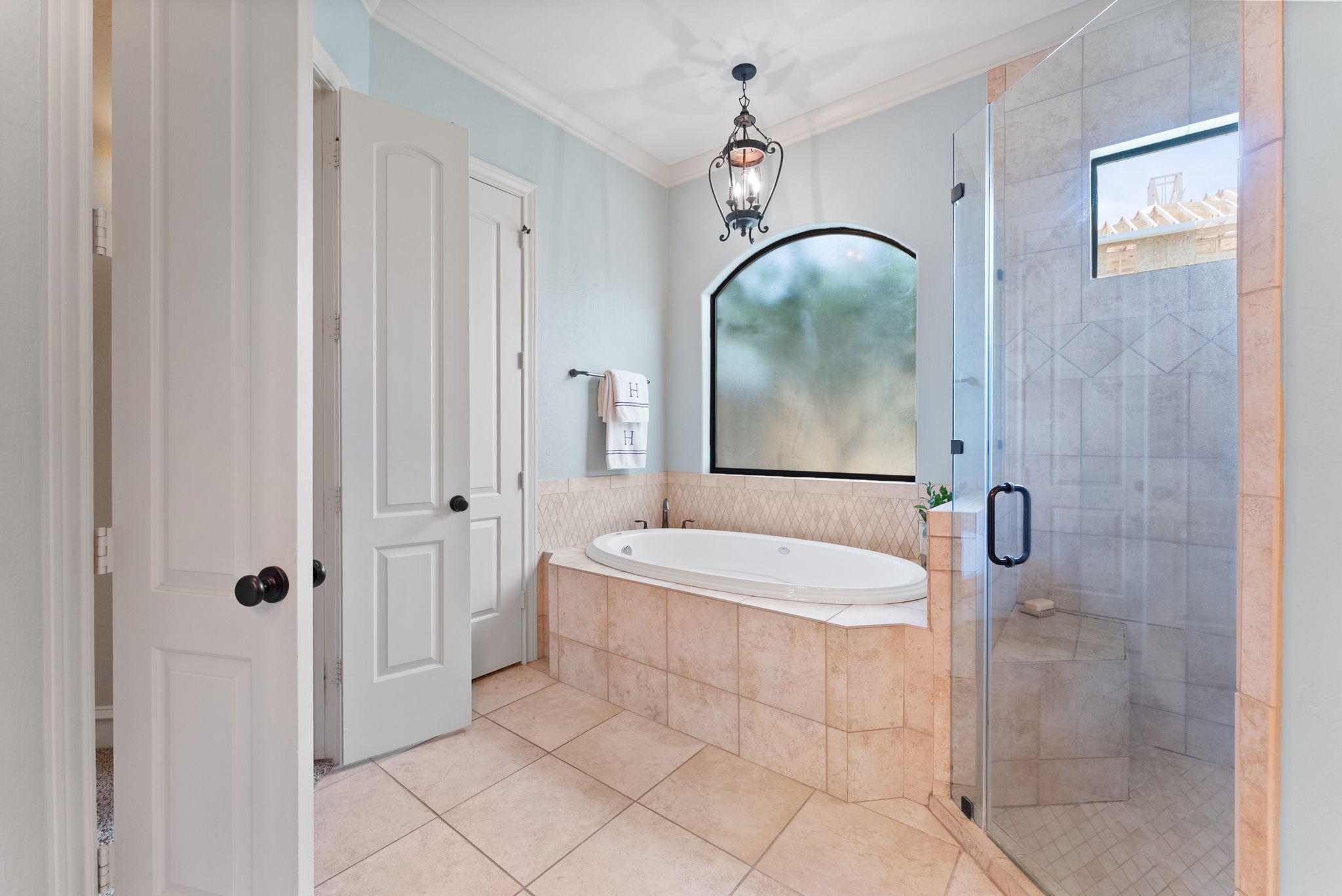 3907 Rayford Road Spring, TX 77386 - Photo 19 of 38 Relax in the large jetted tub beneath a decorative light fixture, or enjoy the oversized walk-in shower with dual shower heads, a bench seat, and tile surround.