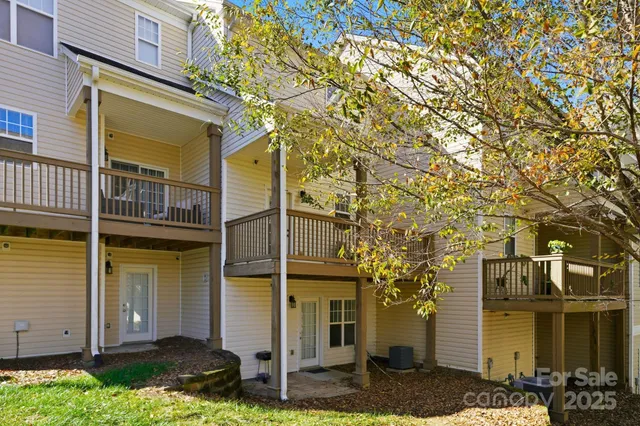 a view of a house with a small yard and large tree