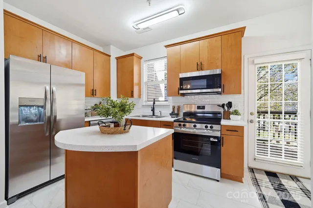 a kitchen with stainless steel appliances granite countertop a stove refrigerator sink and microwave
