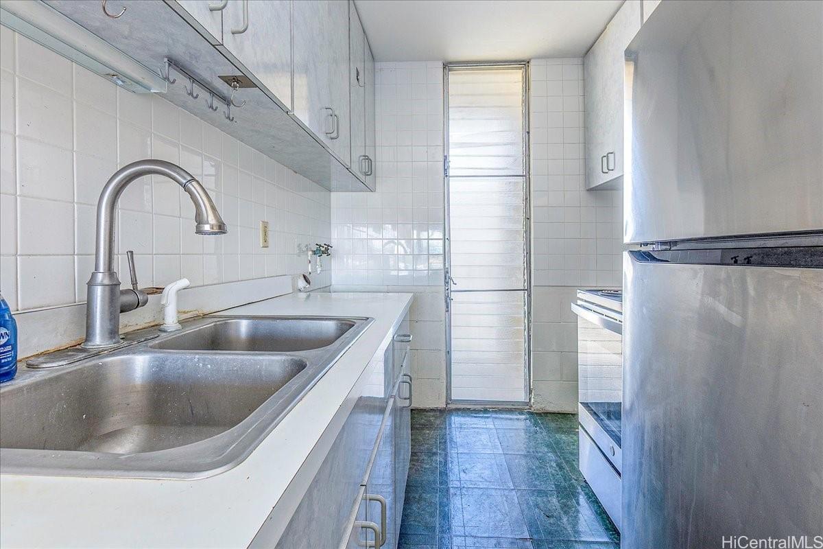 1420 Victoria Street, Unit 1301 Honolulu, HI 96822 - Photo 9 of 20 a kitchen with a sink a refrigerator and cabinets