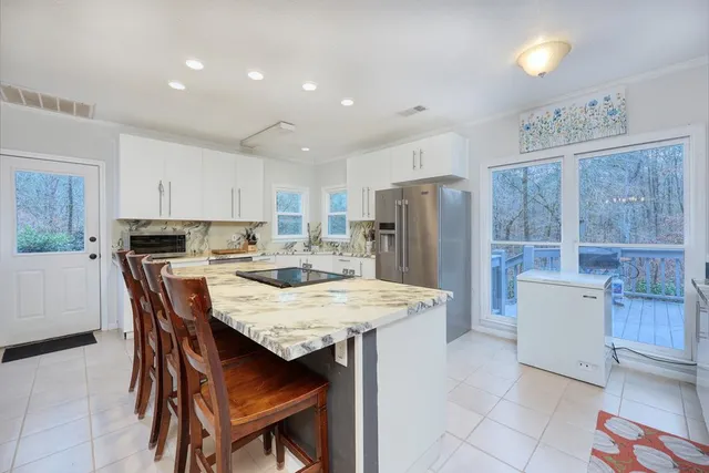 a kitchen with stainless steel appliances granite countertop a table chairs and a refrigerator