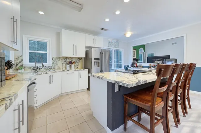 a kitchen with stainless steel appliances kitchen island granite countertop a table chairs a sink dishwasher and cabinets