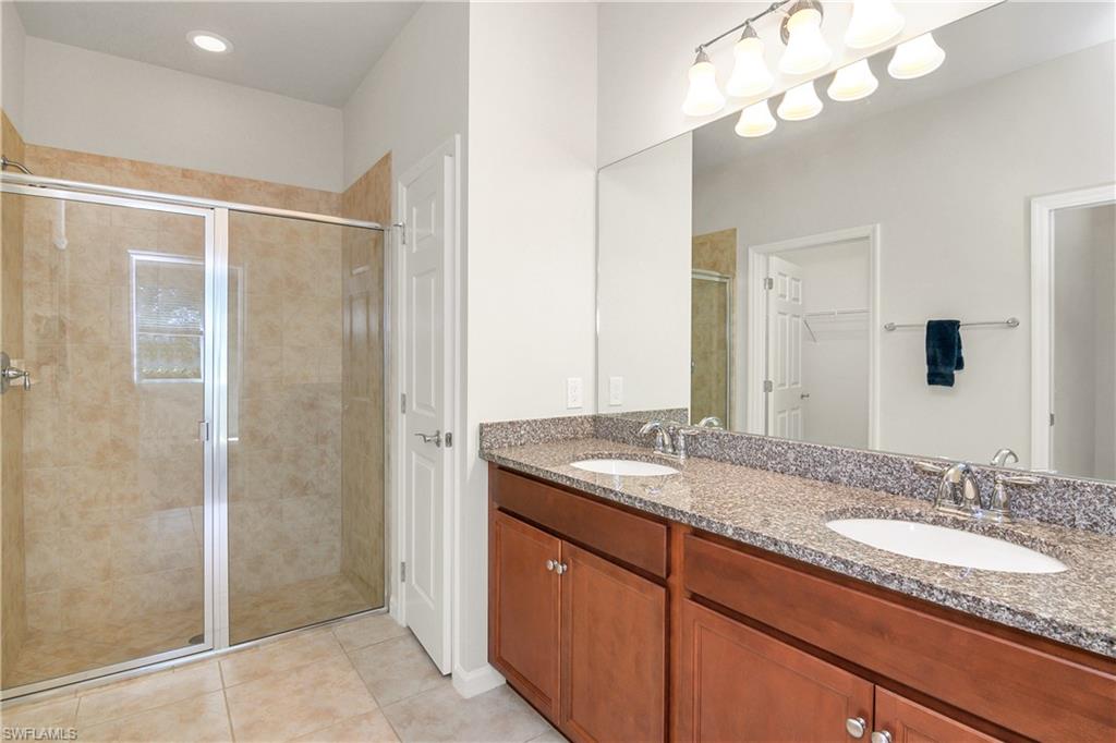 20179 Torch Key Way Estero, FL 33928 - Photo 15 of 25 a bathroom with a granite countertop sink a mirror and a shower
