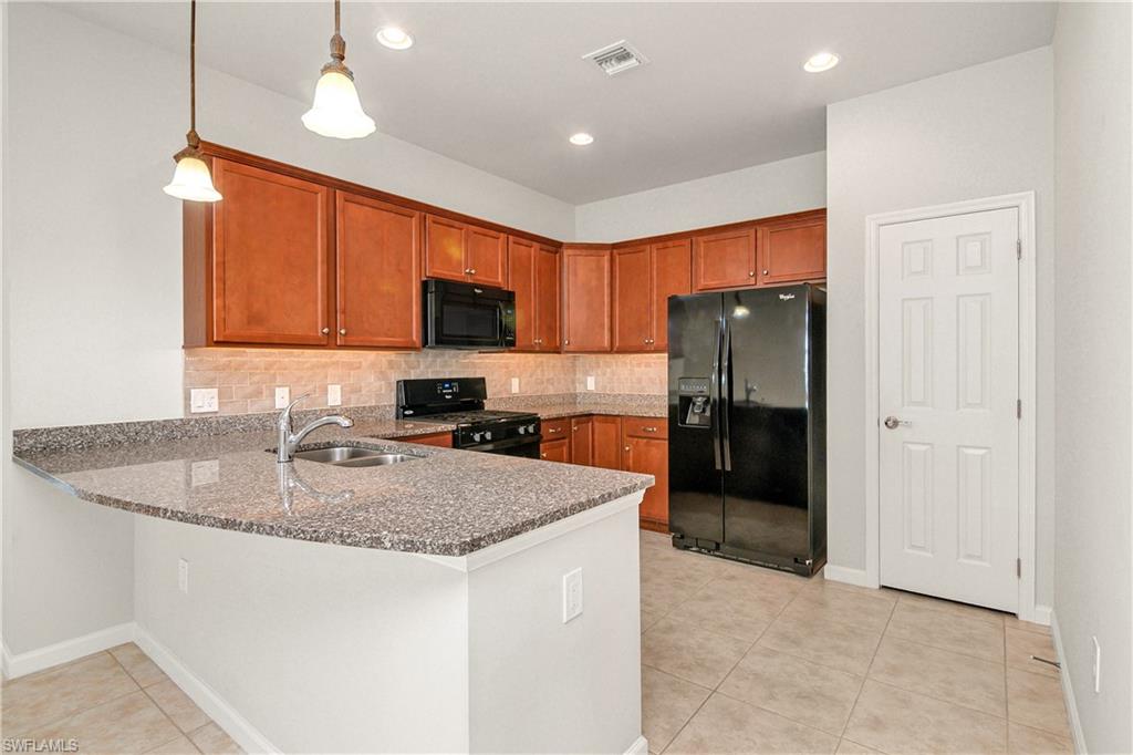 20179 Torch Key Way Estero, FL 33928 - Photo 2 of 25 a kitchen with a refrigerator a microwave a sink and cabinets