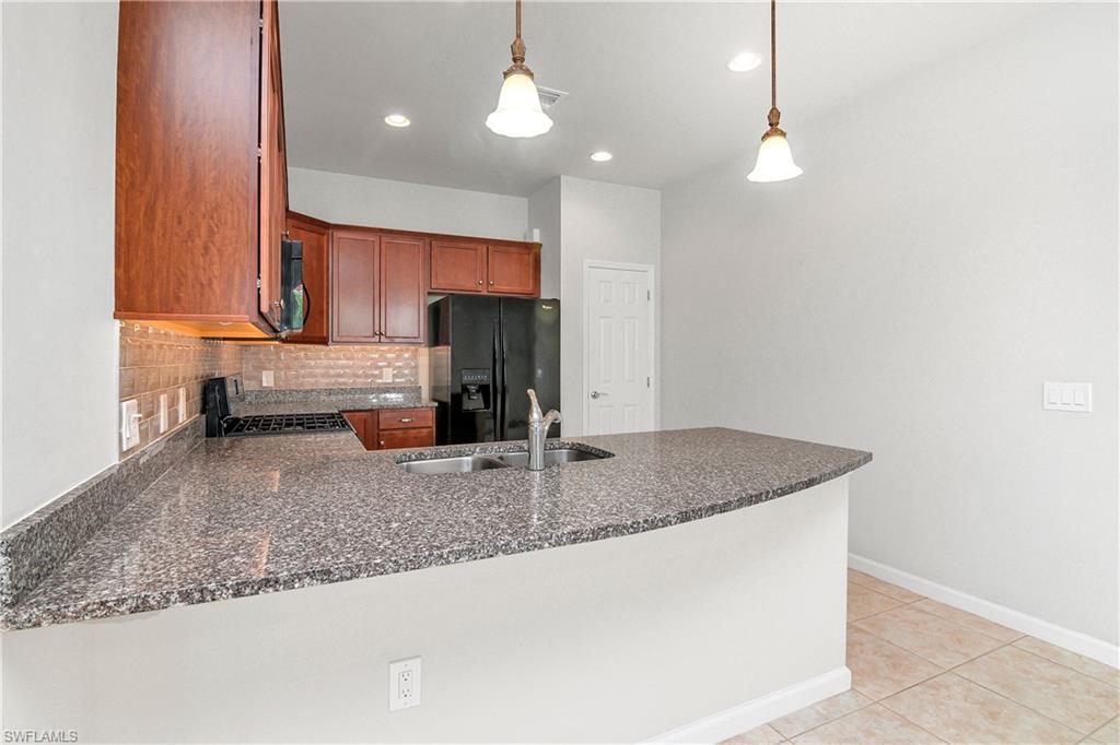 20179 Torch Key Way Estero, FL 33928 - Photo 3 of 25 a kitchen with stainless steel appliances granite countertop a sink a refrigerator and a granite counter tops